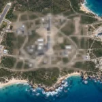 Satellite view of a coastal rocket launch site with its central area pixelated, illustrating Apple Maps blurring military bases